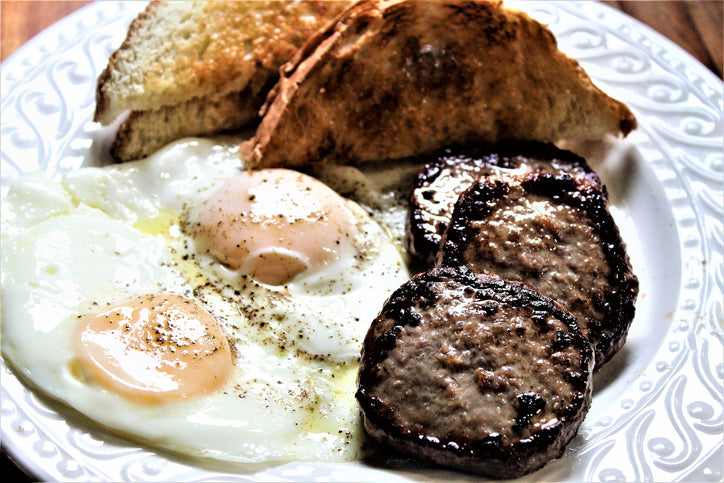 Top-down view of breakfast plate with sausage patties, eggs, and toast