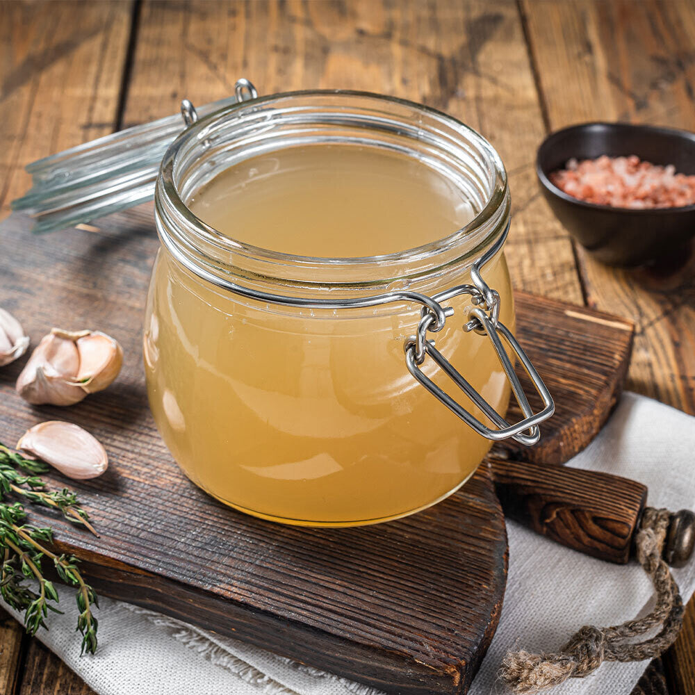 Golden pasture-raised chicken broth in antique mason jar, showing rich color and gelatinous texture