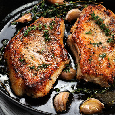 Two pork steaks cooked and plated on a serving dish, ready to eat