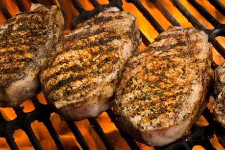 Top-down view of boneless pork chops grilling, with visible grill marks