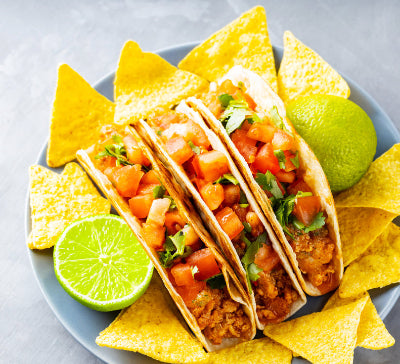 Top-down view of three tacos made with seasoned ground pork and toppings