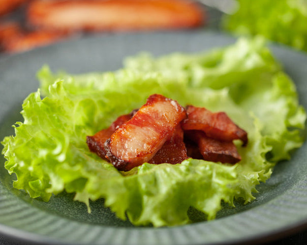 Korean BBQ pork belly on lettuce leaf with grilled edges, ready to wrap