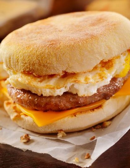 Side view of sausage and egg English muffin breakfast sandwich with country-style pork patty