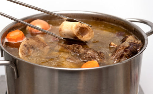 Stock pot with beef soup bones simmering in water with vegetables