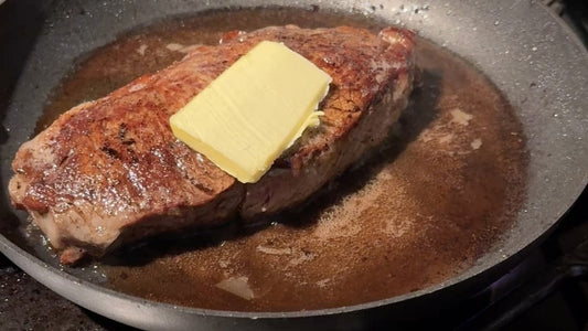 Grass-fed steak frying in a pan with grass-fed butter melting on top, perfect for keto diets.