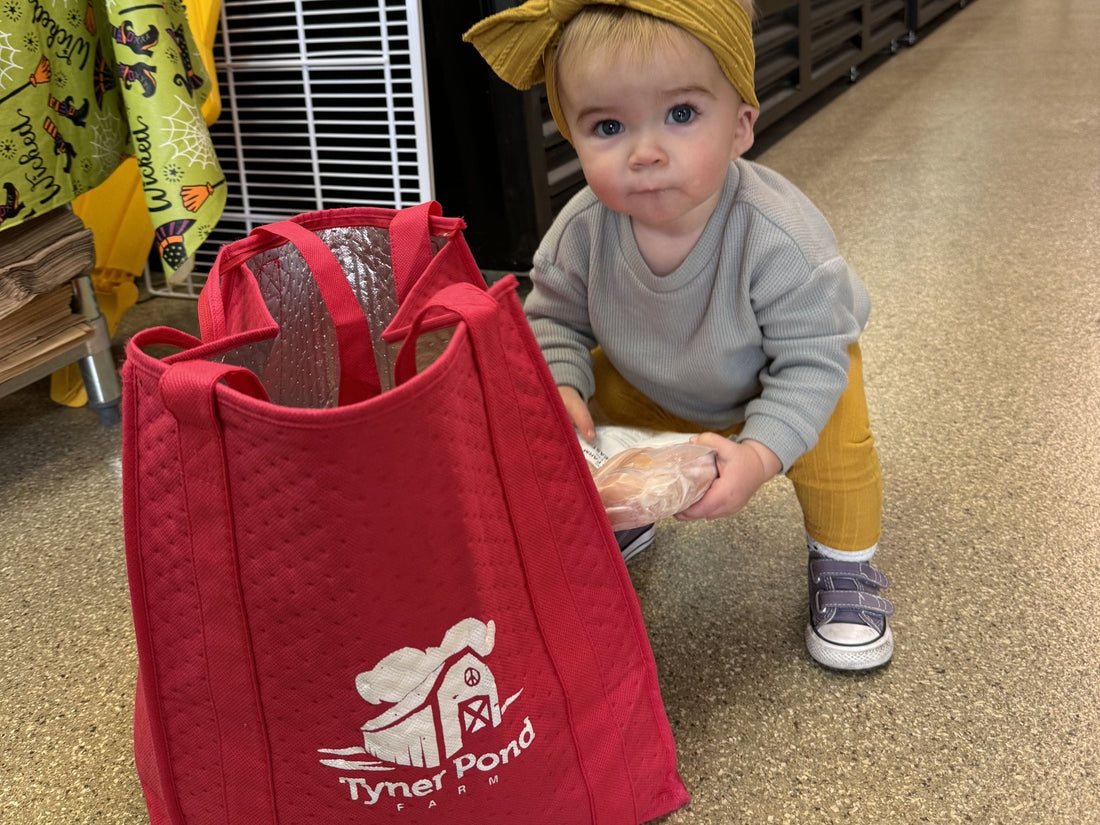 Baby in Tyner Pond Farm store holding a package of pasture-raised meat, exploring nutrient-dense food options for baby-led weaning.