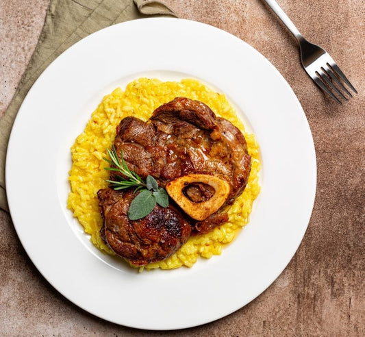 Braised beef ossobuco served on a bed of creamy polenta, garnished with fresh herbs.