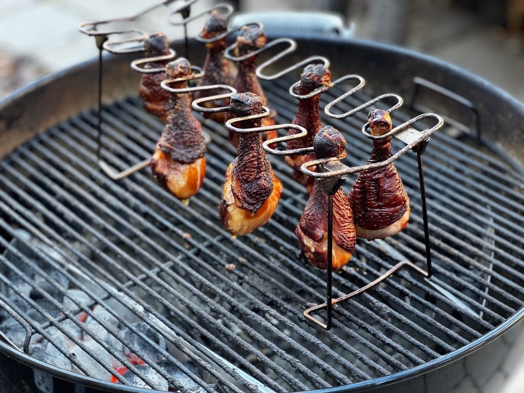 Pasture-raised smoked chicken legs hanging on a grill, prepared for keto-friendly snacks and meals.