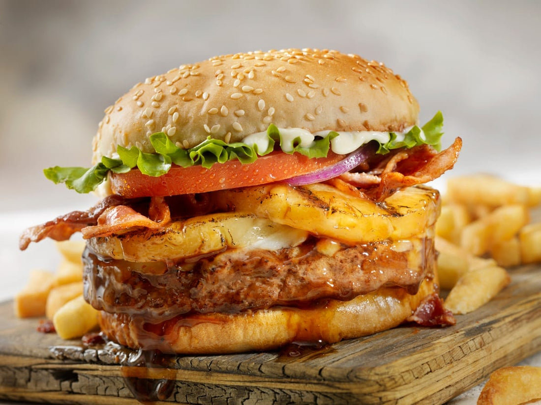 Hawaiian style pork burger with grilled pineapple, bacon, lettuce, and tomato on a sesame seed bun