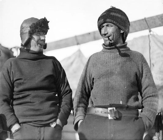 Two members of Shackleton’s crew smiling with pipes, showcasing camaraderie and positivity during the harsh conditions of the Endurance expedition