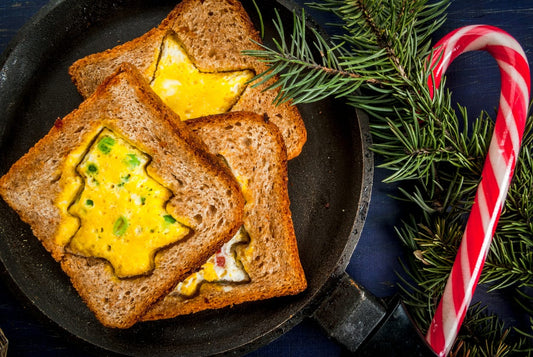Scrambled egg-filled toast in Christmas tree shapes, cooked in whole-grain bread, served in a festive setting with a candy cane and greenery