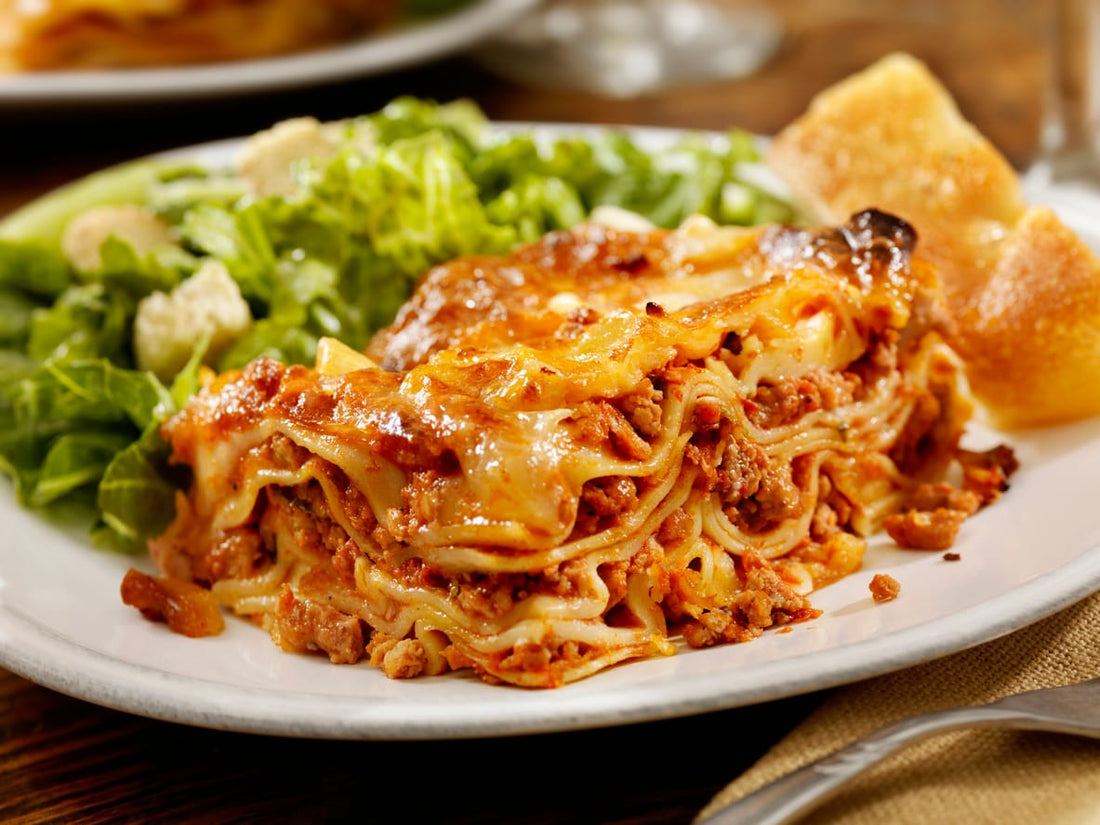 A slice of ground turkey lasagna served with a fresh green salad and bread, ideal for a pre-Thanksgiving family meal