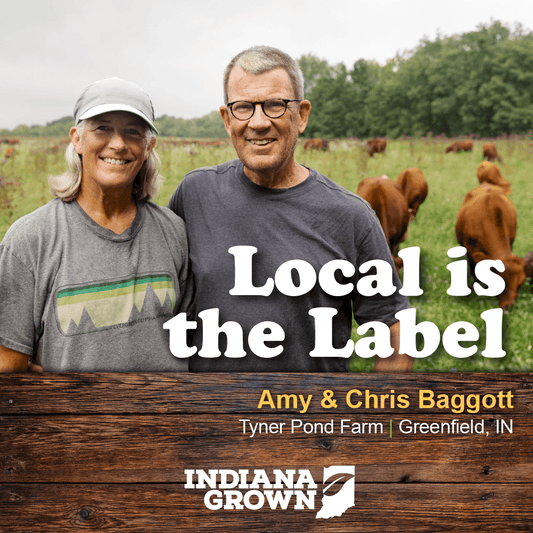 Amy and Chris Baggott of Tyner Pond Farm standing in a pasture with cows in the background, featured in the Indiana Grown statewide promotion. The text reads "Local is the Label."