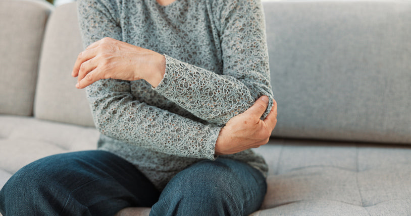 Person experiencing elbow joint discomfort, illustrating arthritis-related inflammation and joint pain discussed in relation to diet and food choices.