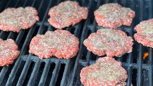 Grassfed beef burgers cooking on a grill, illustrating a discussion about bioavailable protein and nutrient-dense food from Tyner Pond Farm in Central Indiana.