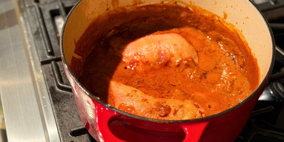 Bone-in chicken leg quarters simmered in a coconut cream curry sauce in a Dutch oven
