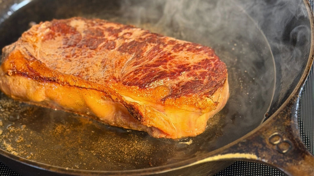Grass-fed steak cooking in a cast-iron skillet, representing a whole-food approach to metabolic health