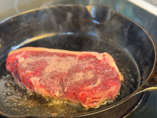 Grass-fed ribeye searing in a Lancaster No. 8 cast iron skillet