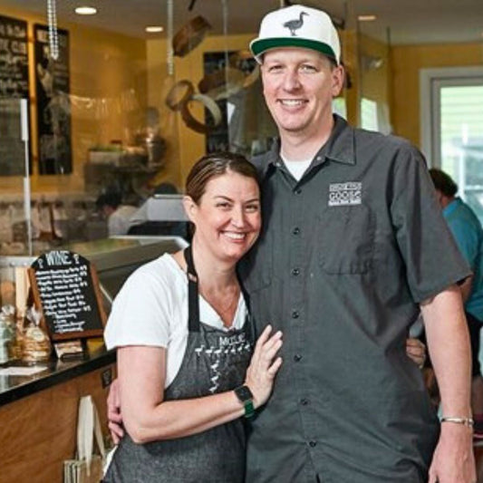 Two people smiling together inside a food shop