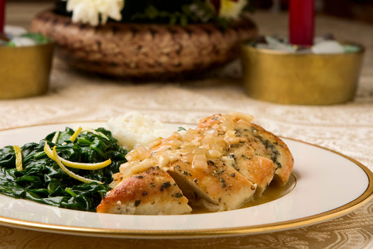 Pan-seared chicken breasts with onion, lemon, and herb sauce served on a plate