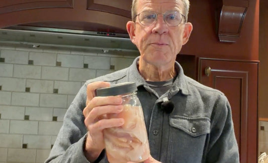 Chris Baggott holding a mason jar with boneless skinless chicken breasts in a simple wet brine.