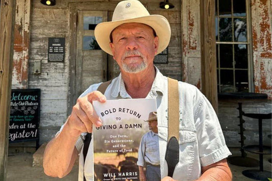 Will Harris of White Oak Pastures holding A Bold Return to Giving a Damn outside the farm’s general store in Bluffton, Georgia.