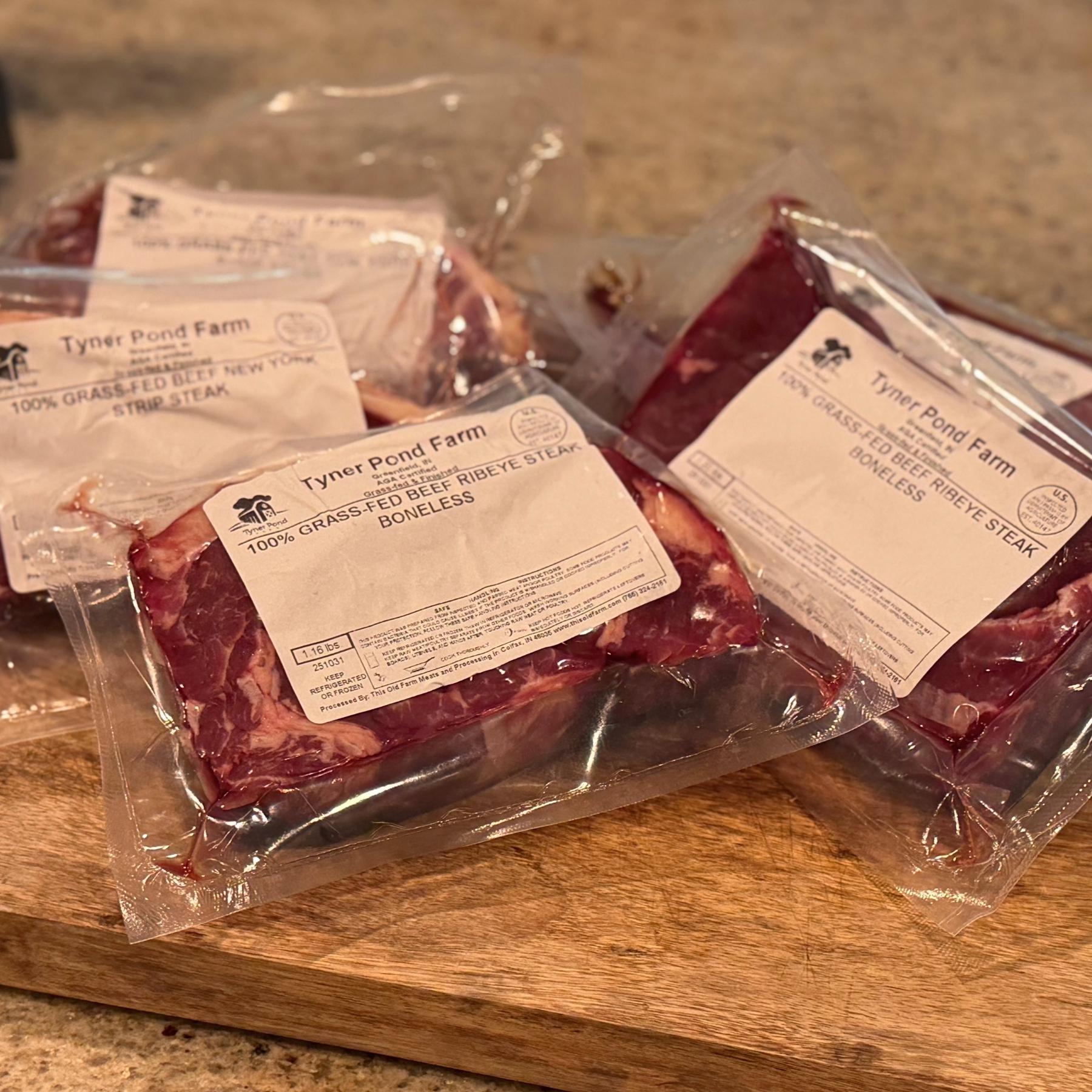 Packaged beef steaks from Tyner Pond Farm on a wooden cutting board.