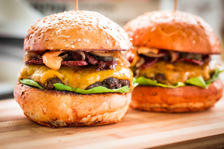 Grilled 4 oz grassfed burger in sesame bun with tomato and onion, sourced from Tyner Pond Farm in Indiana