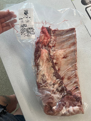 Porks Spare Ribs package on a white surface with a hand holding it.