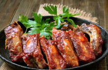 Cooked country style bone-in pork ribs with BBQ sauce in cast iron skillet, ready to serve