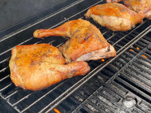 Leg quarters grilling on upper rack, pasture-raised and ready to serve