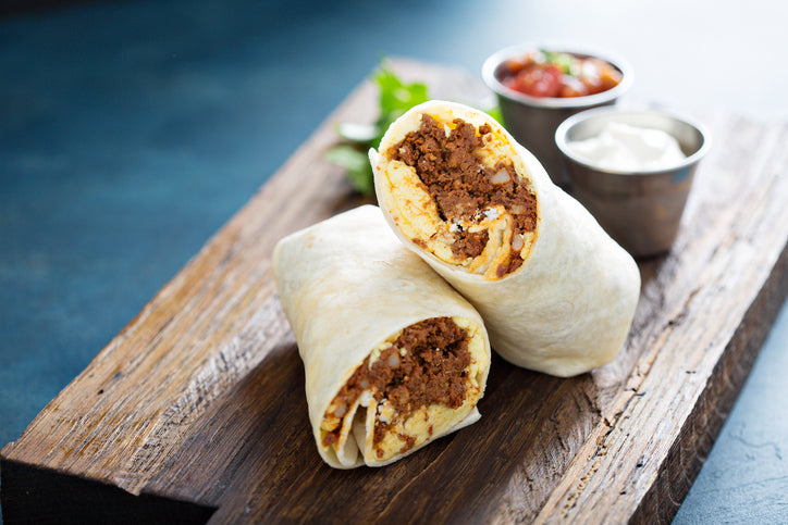 Cooked chorizo breakfast burrito sliced open on cutting board