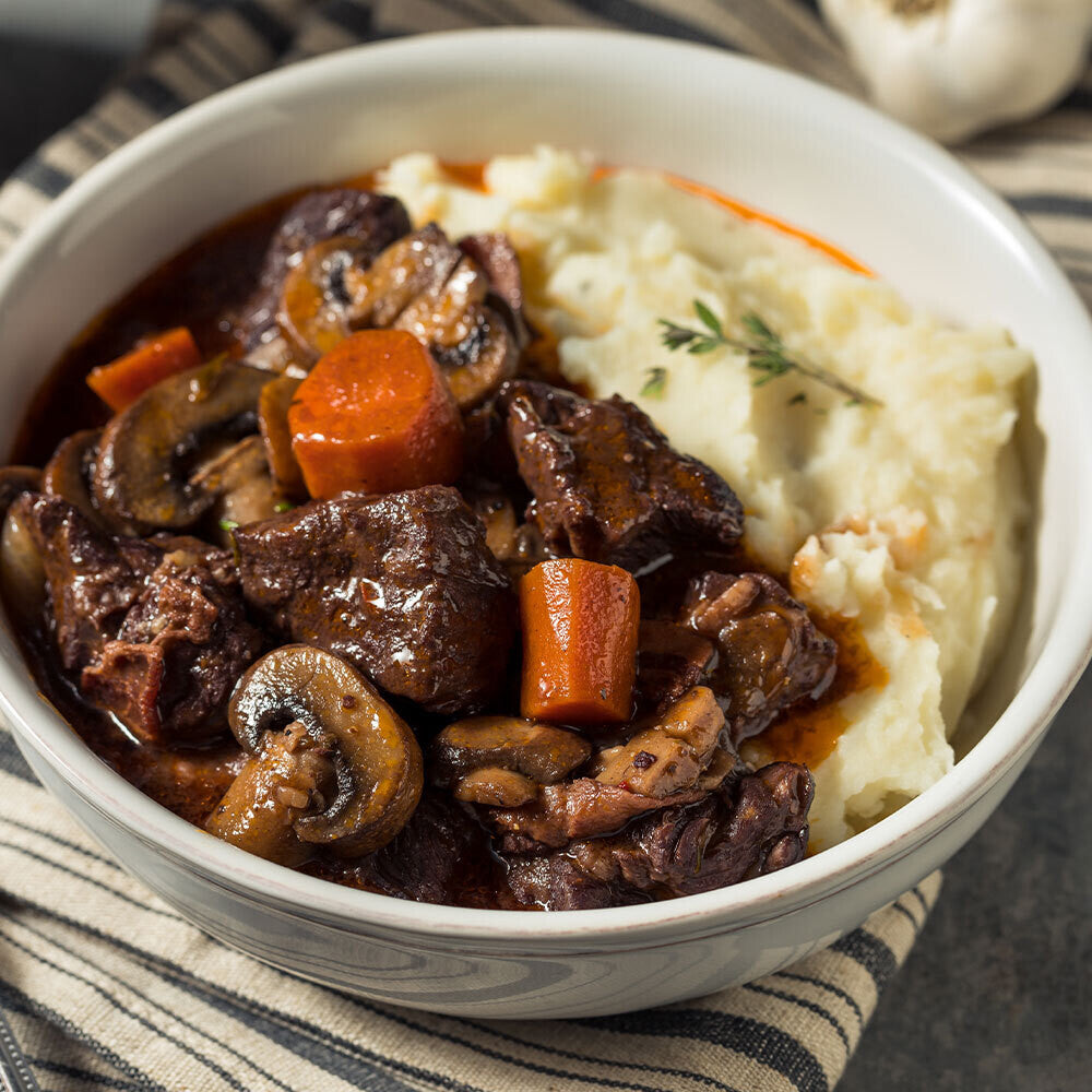 Cooked grassfed beef stew meat served in a bowl with mashed potatoes, raised on pasture at Tyner Pond Farm