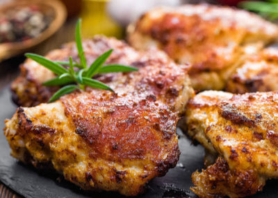 Golden brown pasture-raised chicken thighs on serving platter, skin-on and bone-in
