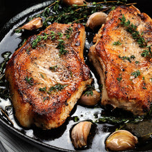 Two pork steaks cooked and plated on a serving dish, ready to eat