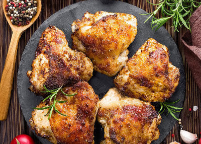 Cooked pasture-raised chicken thighs plated and ready to serve, crisp skin from outdoor-raised birds