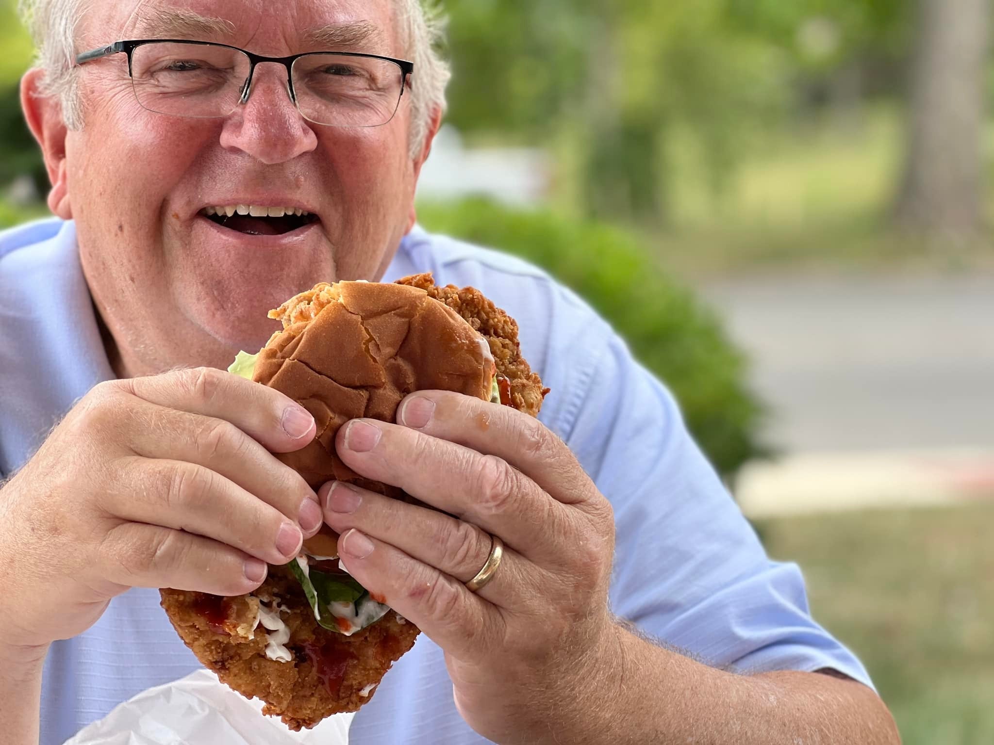 Man eating Indiana-style breaded pork tenderloin sandwich outdoors