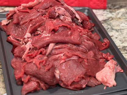 Raw 100% grass-fed rump roast sliced into thin strips for stir fry on a baking sheet at Tyner Pond Farm.