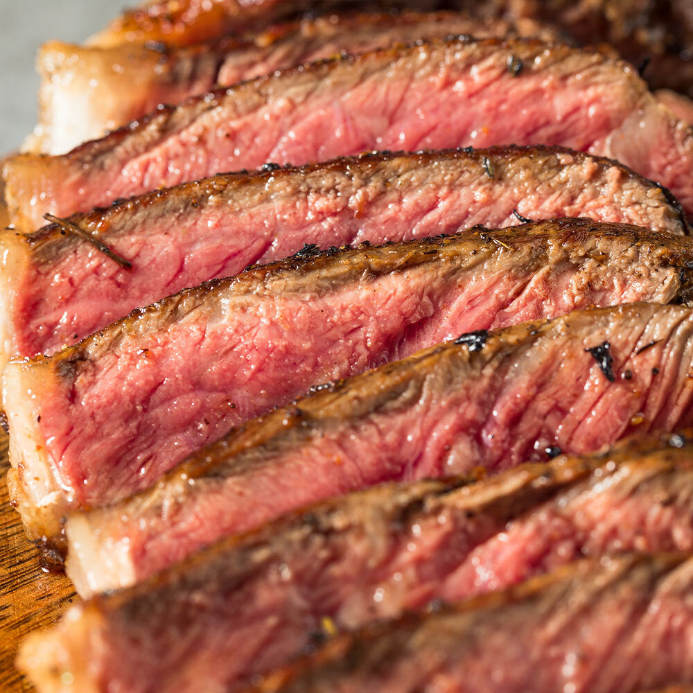 Cooked grassfed New York Strip Steak sliced on a plate, raised on pasture without grain or antibiotics