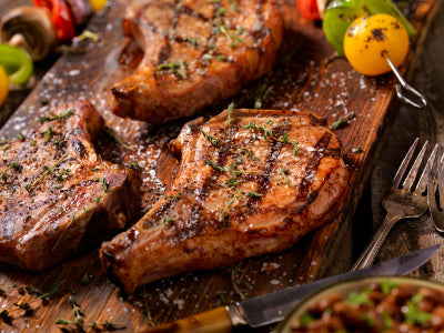 Grilled bone-in pork chop glazed with barbecue sauce, charred and ready to serve