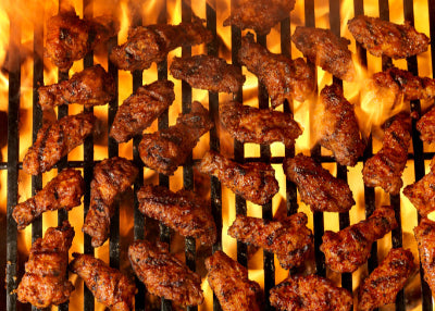 Grilled pasture-raised chicken wings cooking over open flame, top view