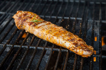 Pork tenderloin grilling over open flame, browning evenly