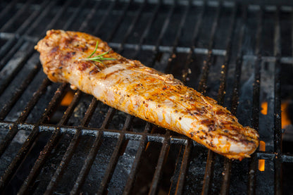Pork tenderloin grilling over open flame, browning evenly