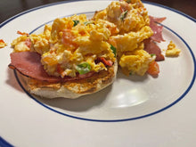 Open-faced ham and egg breakfast sandwich on English muffin with melted cheese