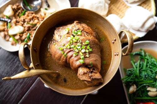 Ham hock simmering in a stew bowl with broth and vegetables