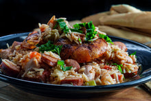 Jamaican bratwurst sliced over a plate of jambalaya rice, bright and colorful