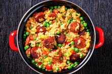 Top-down view of jambalaya with sliced kielbasa in red Dutch oven