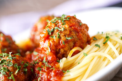 Close-up of meatball made with ground pork on top of spaghetti