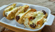 Philly cheesesteak brats in buns smothered in melted cheese and onions