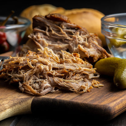 Side view of pulled pork on cutting board, showing strands and bark from smoking